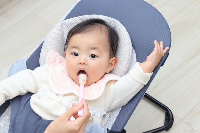 バウンサーに座る赤ちゃんを見守る親のイメージ