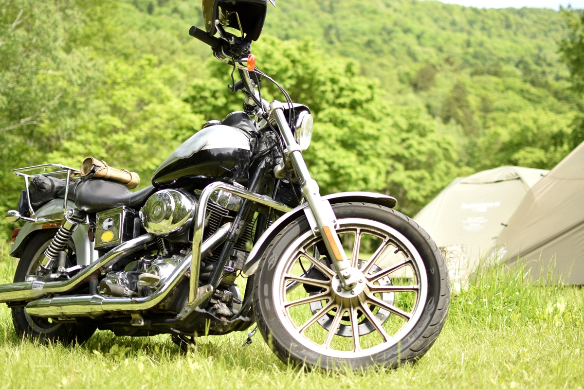 泊数に合わせた荷物を積んでキャンプ場に停めたバイクのイメージ