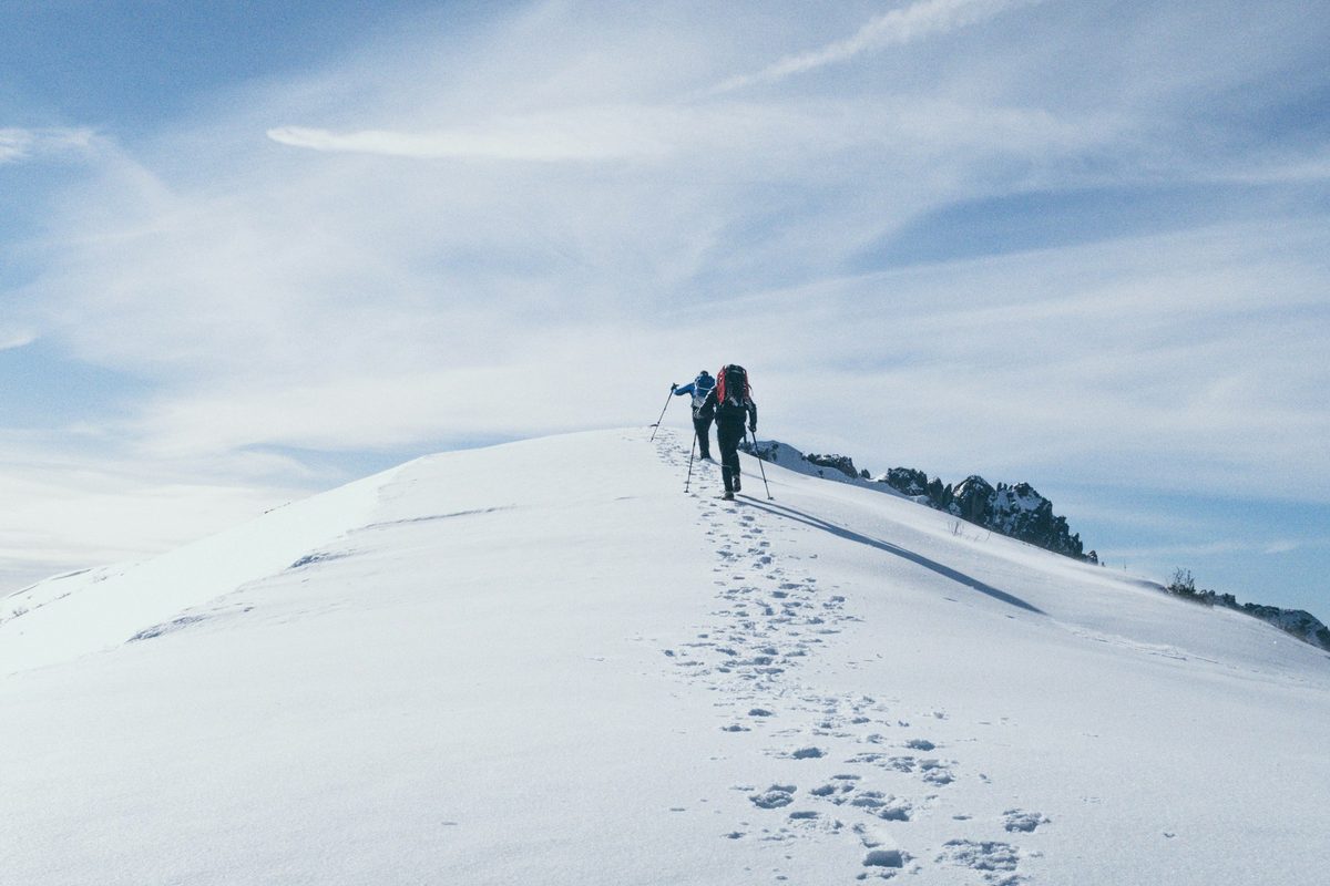 道標が雪に隠れた雪山を登る登山者